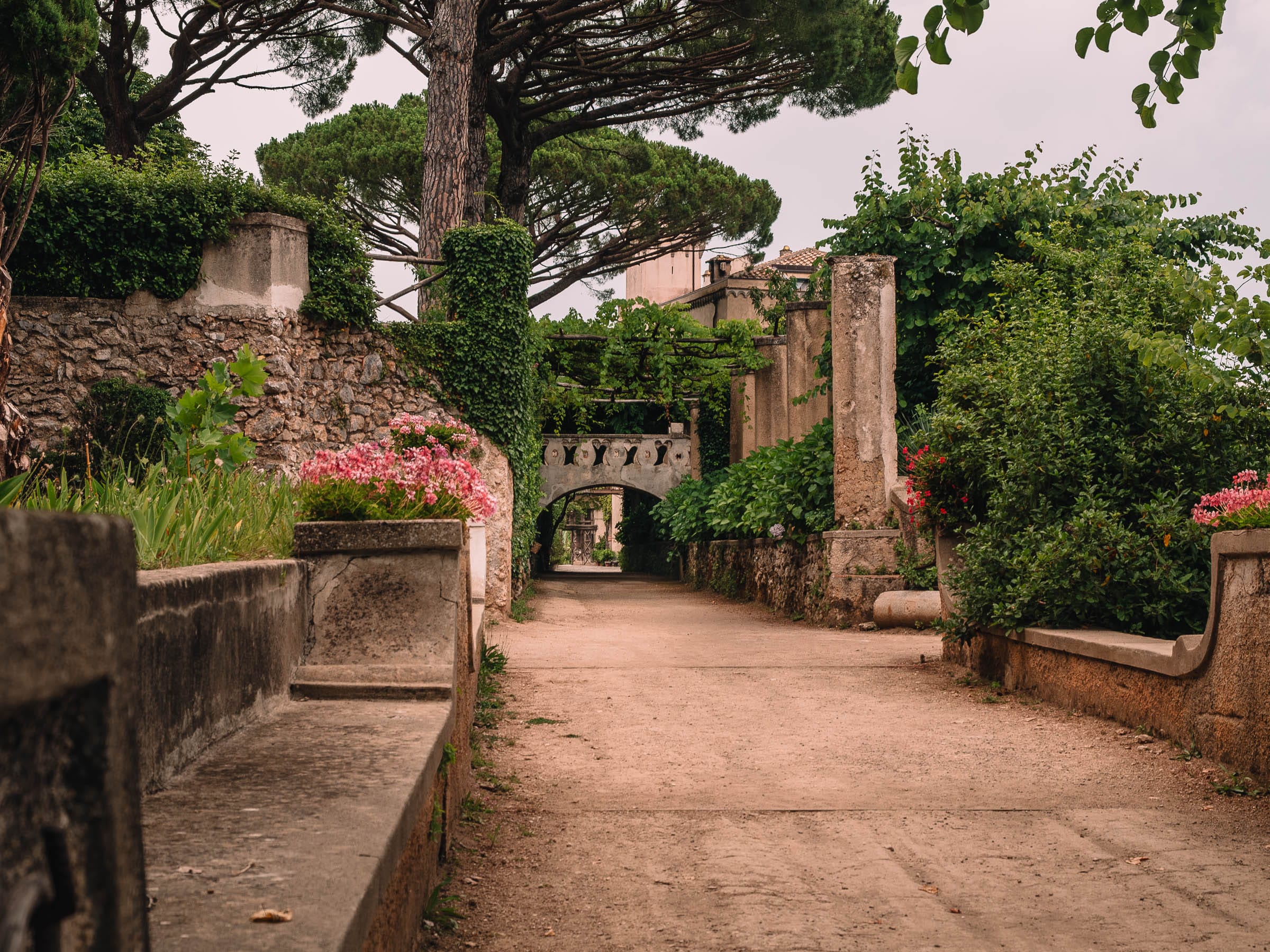 Gefasster Gartenweg zwischen Mauern und dichter Vegetation in der Villa Cimbrone
